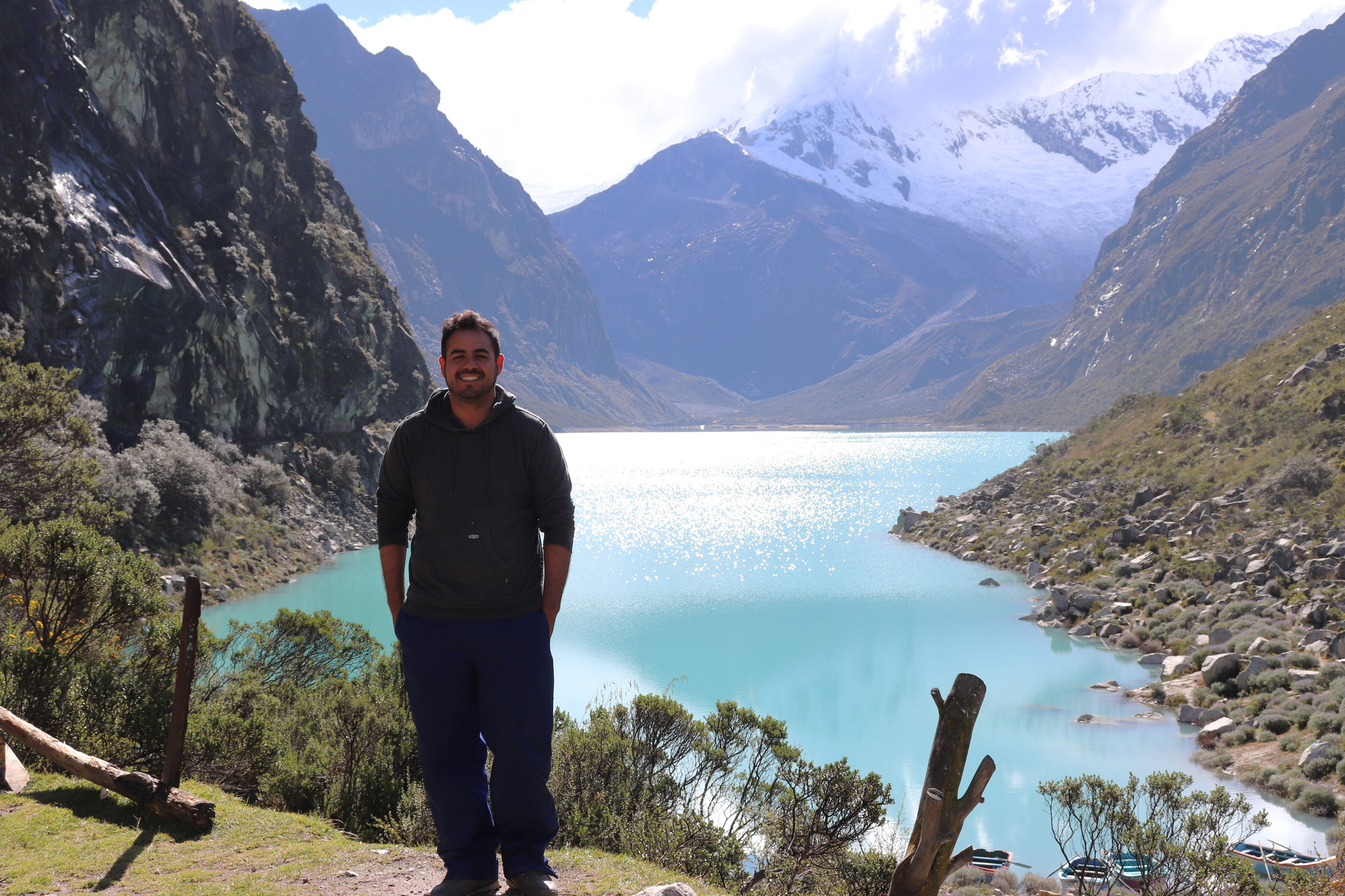 A man stands in front of a lake. 
