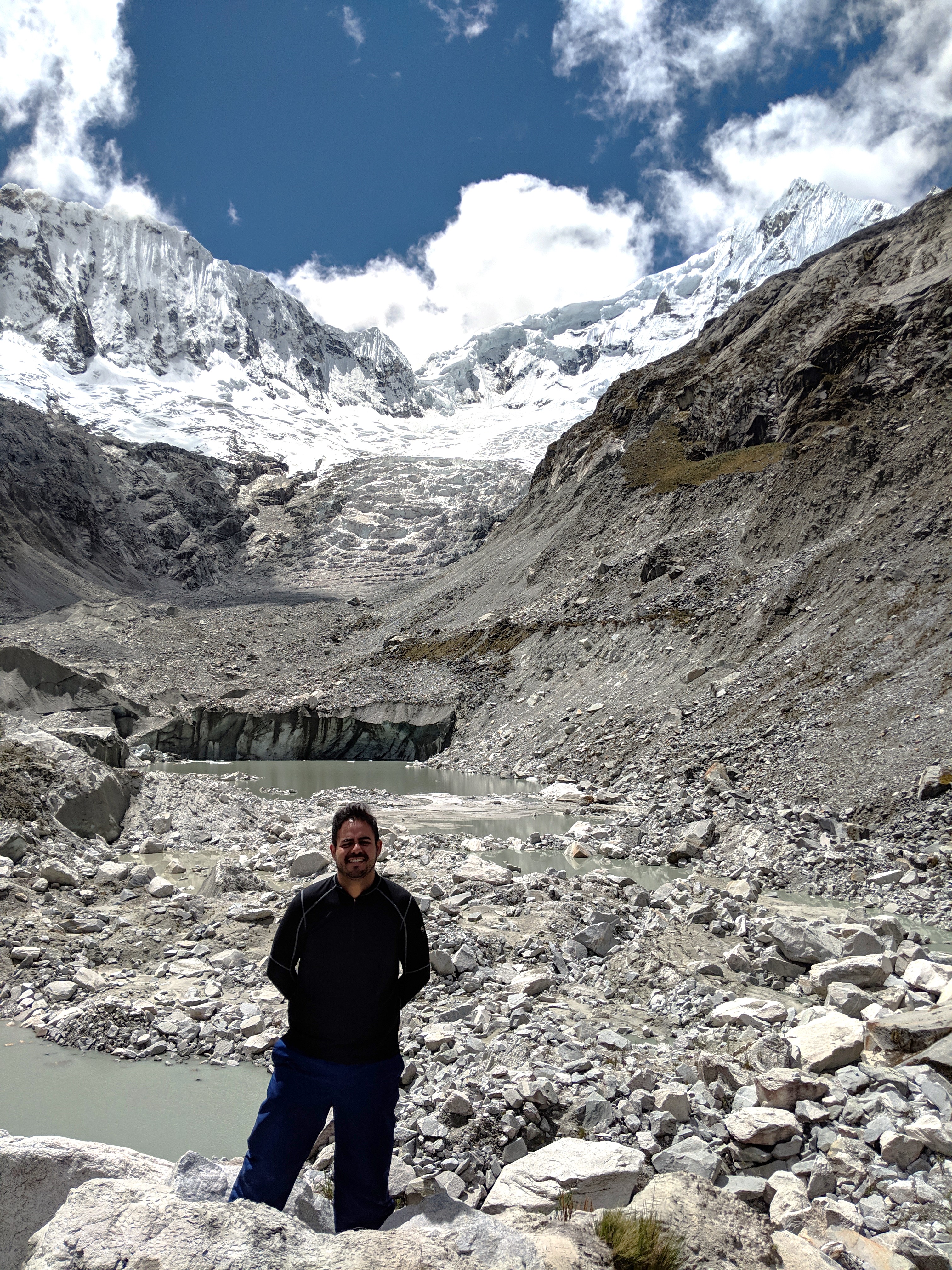 A man stands in front of a glacier.
