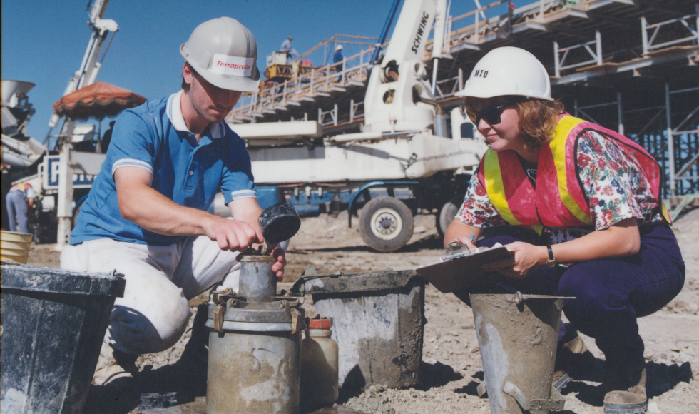 Two worker in hard hats, working on the development of a highway.