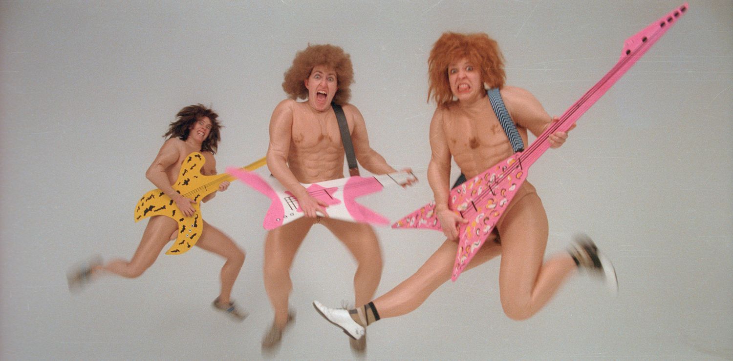 Three people holding electric guitars and leaping in the air