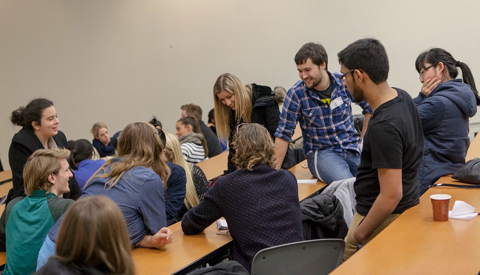 Students talking amongst themselves in a lecture hall.