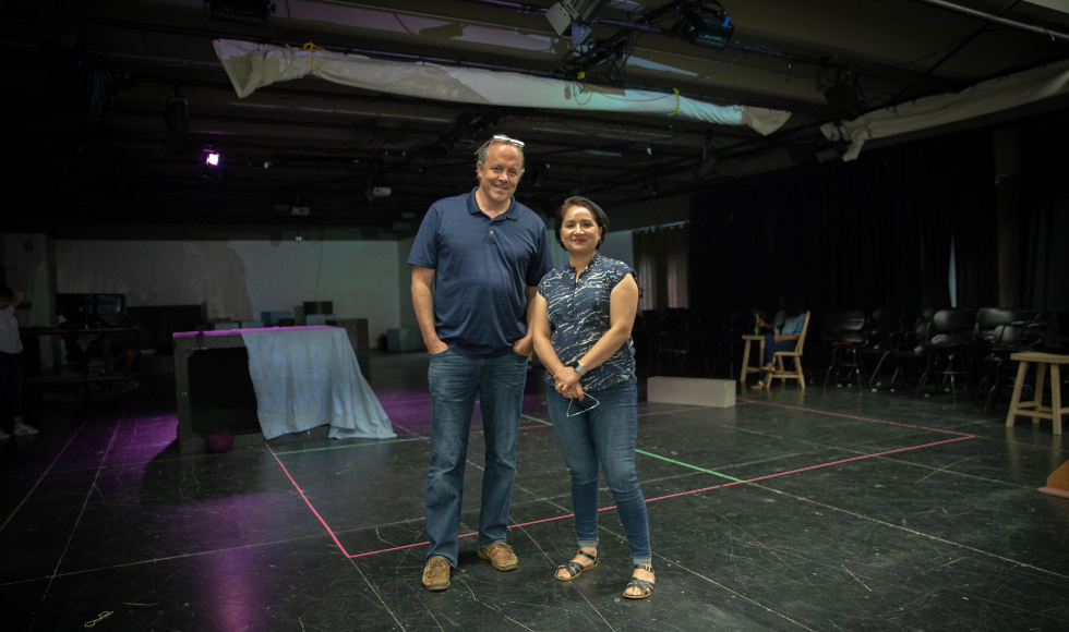 Man and woman stand in theatre studio space