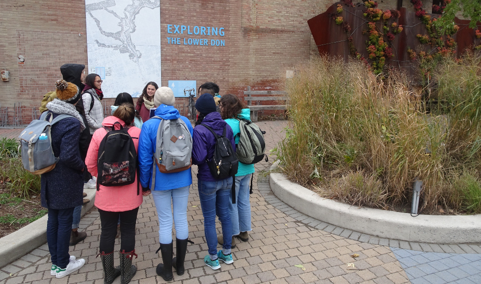 A group of students stands under a map that says exploring the lower don