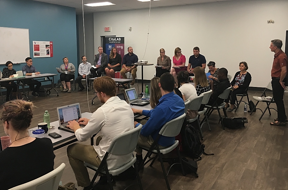 Students in the Semester@CityLAB course meet for the first time with staff from the City of Hamilton in the CityLAB space in downtown Hamilton. They are sitting around a table and talking on the first day of class last Fall.