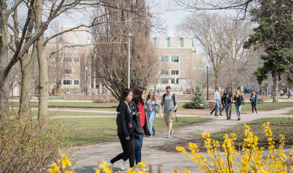 Students walk across McMaster campus in early spring