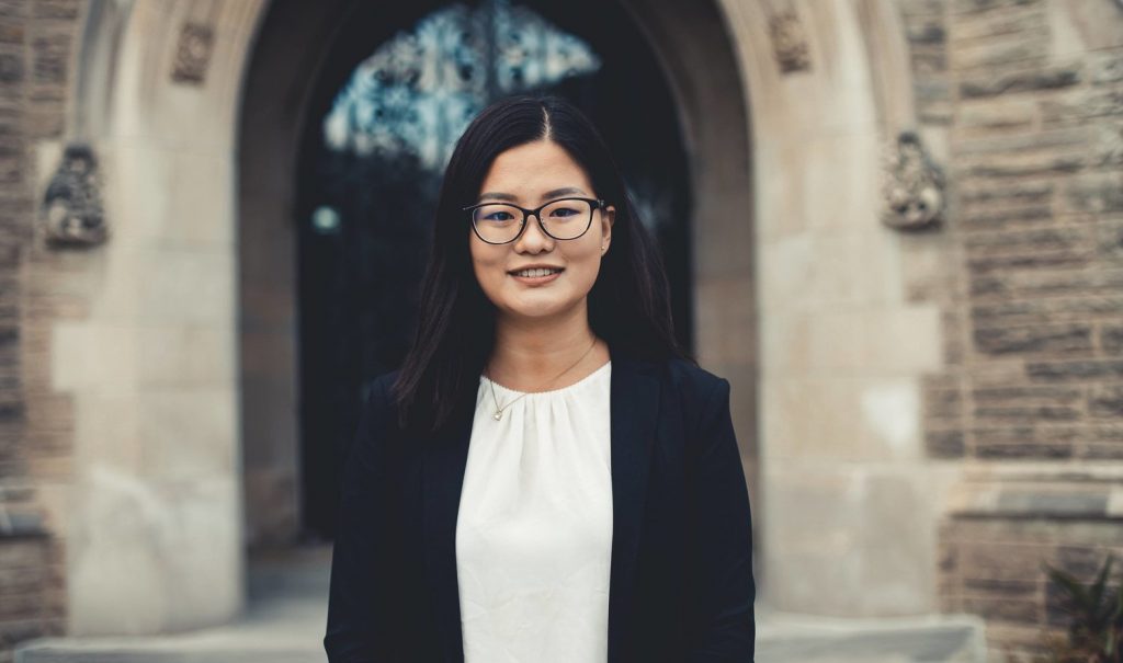Angelina Zhao standing in front of the doors of Hamilton Hall