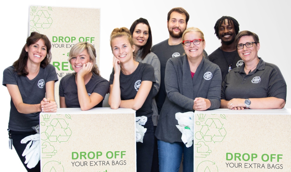 Eight Campus Store staff members stand behind boxes of reused plastic bags