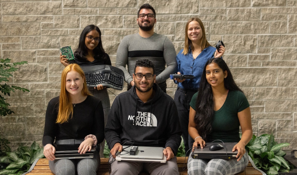 Six students hold laptops and keyboards