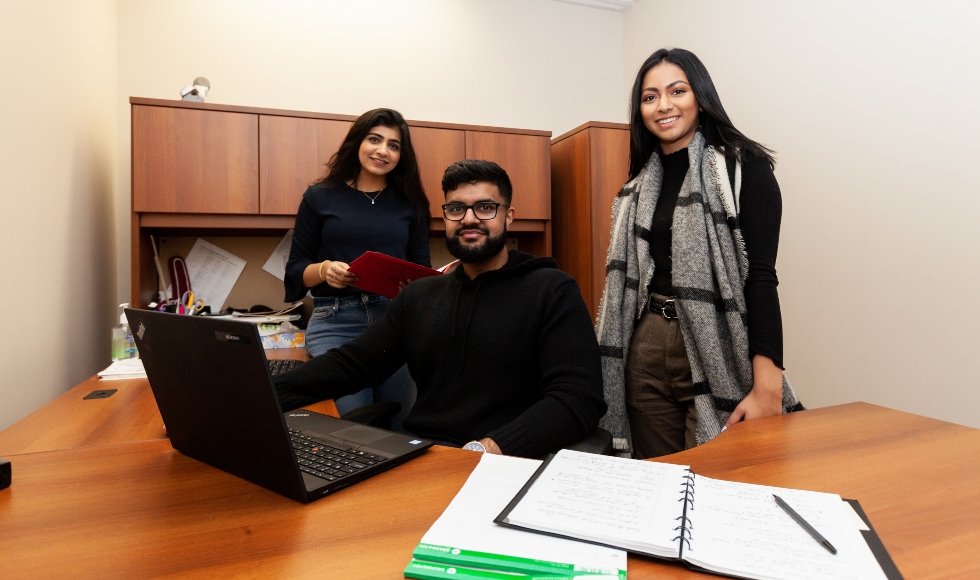 Three financial staffers pose with a laptop in a hospital office