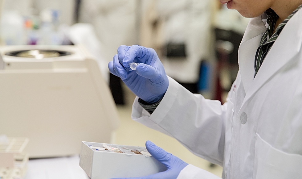 Photo of a graduate student in a lab coat in Jonathan Bramson's lab