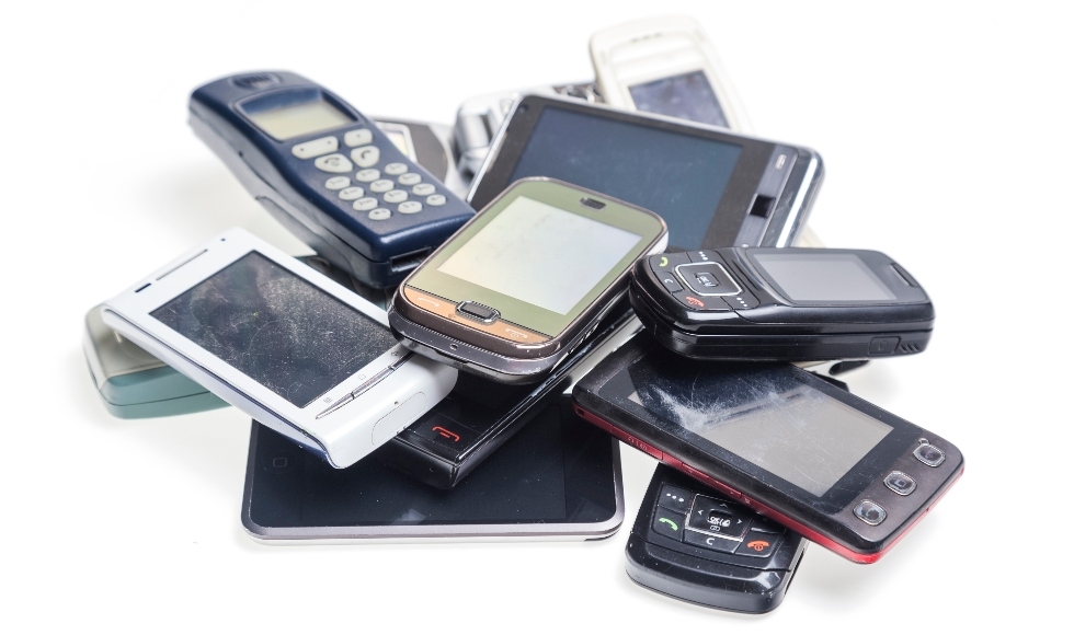 Image of a pile of old smart phones and tablets with shattered screens