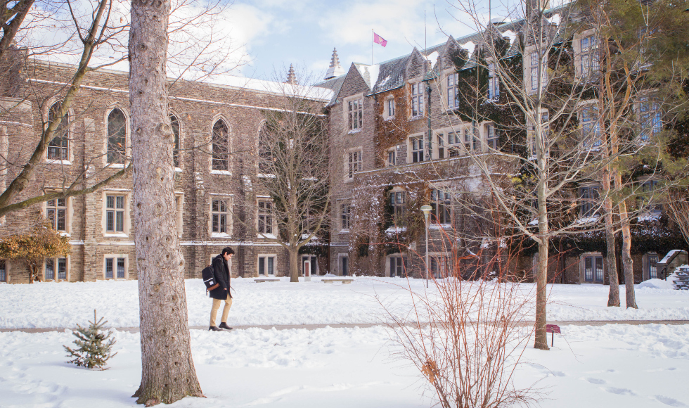 A person walks behind University Hall in the winter