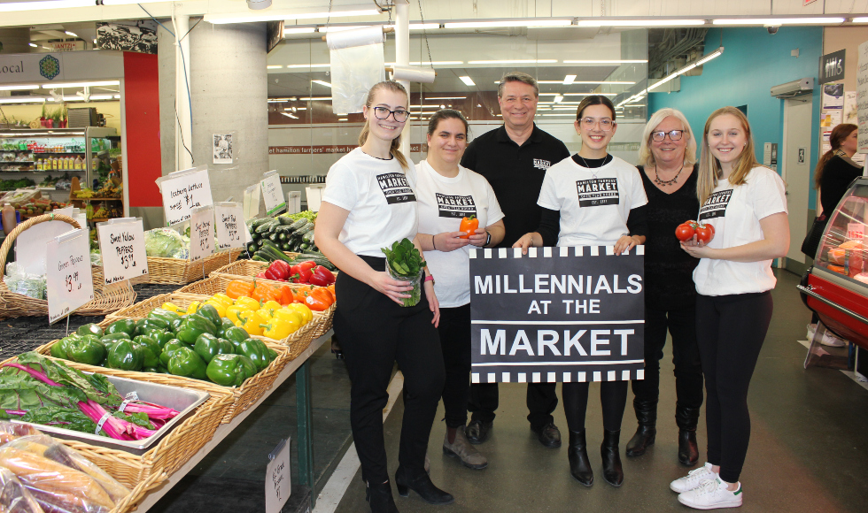 A group of five people smiling and holding a sign that says 