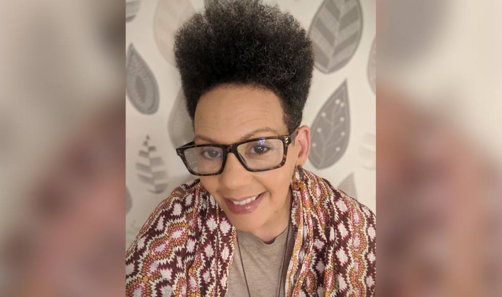 A smiling woman wearing glasses and a colorful shawl