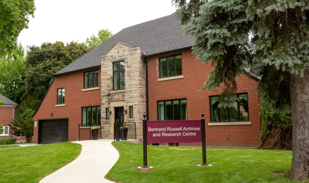 A large house-shaped building with a sign outside that says Bertrand Russell Archives and Research Centre.