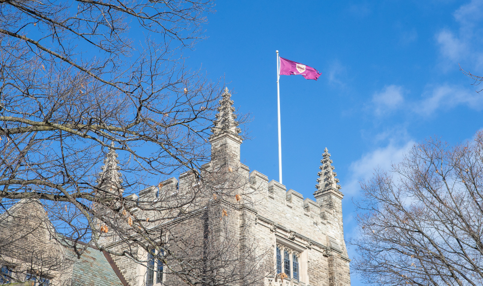 THe McMaster flag, flying on top of UNiversity Hall against a blue sky