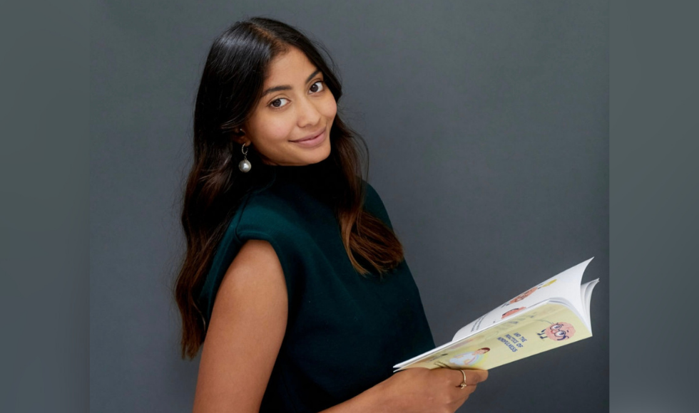 A photo of McMaster valedictorian Shania Bhopa holding a book and smiling at the camera.