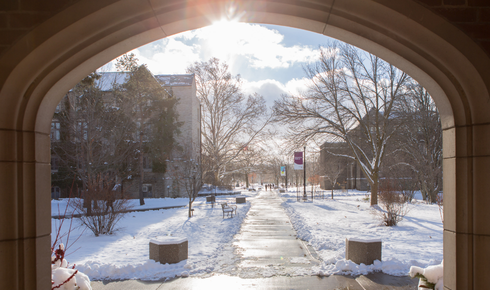 Campus walkway on a snowy day, seen through an archway.