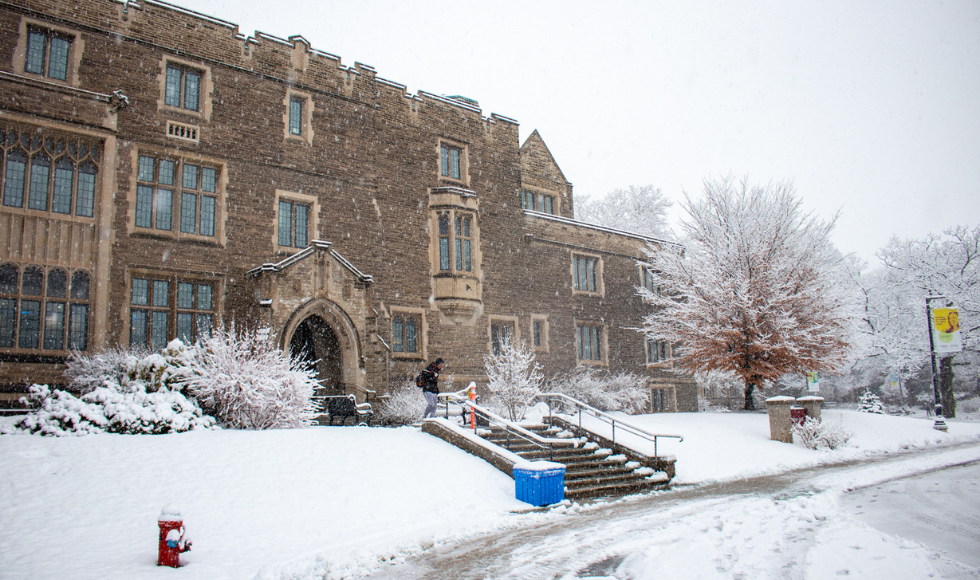 Historic building on university campus surrounded by snow.