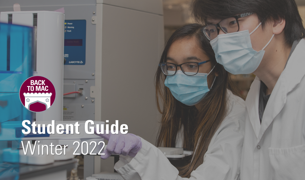 A photo of two students, both wearing masks and lab coats. They are examining a piece of machinery. Text in the bottom left corner reads 'Back to Mac Student Guide Winter 2022'
