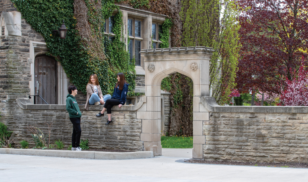 Three smiling students near Edwards Arch on campus