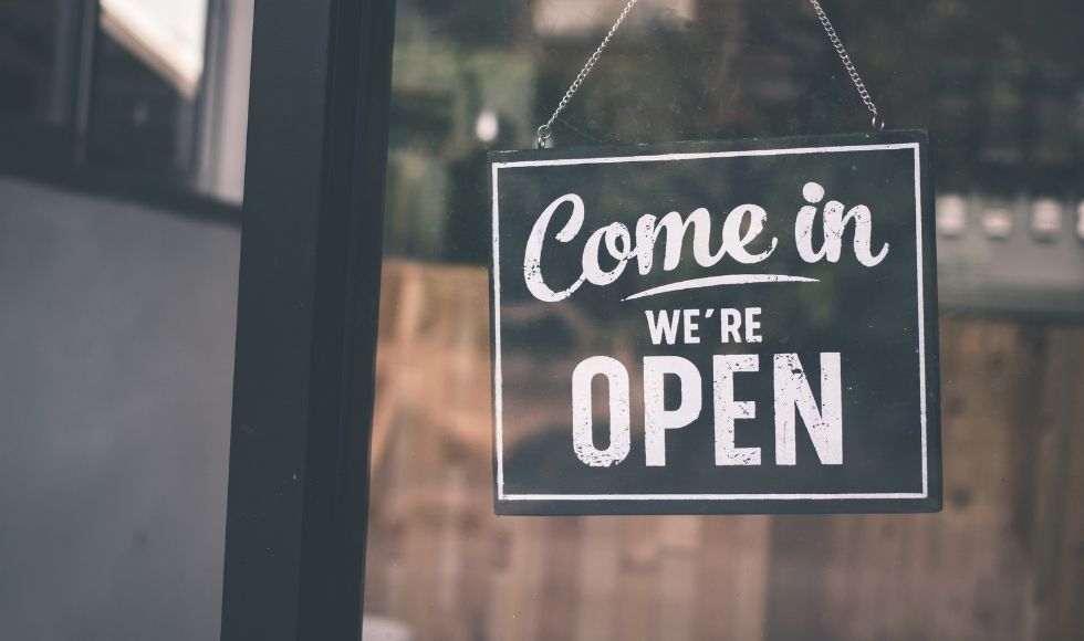 A photo of a sign hanging in a window that reads 'Come in. We're open'