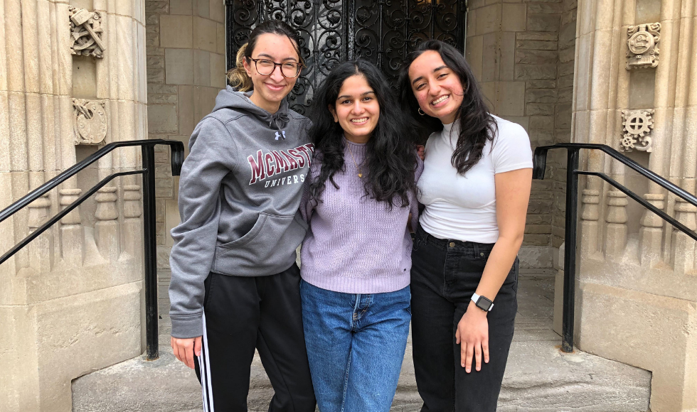 Three smiling McMaster students posing for a picture with their arms around each other