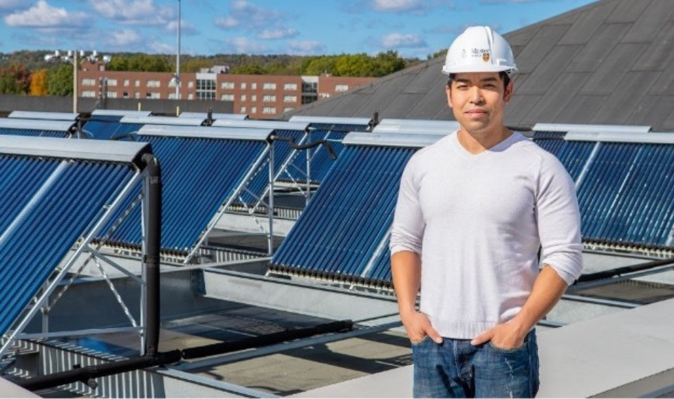 A man in a hard hat standing on a rooftop with solar panels