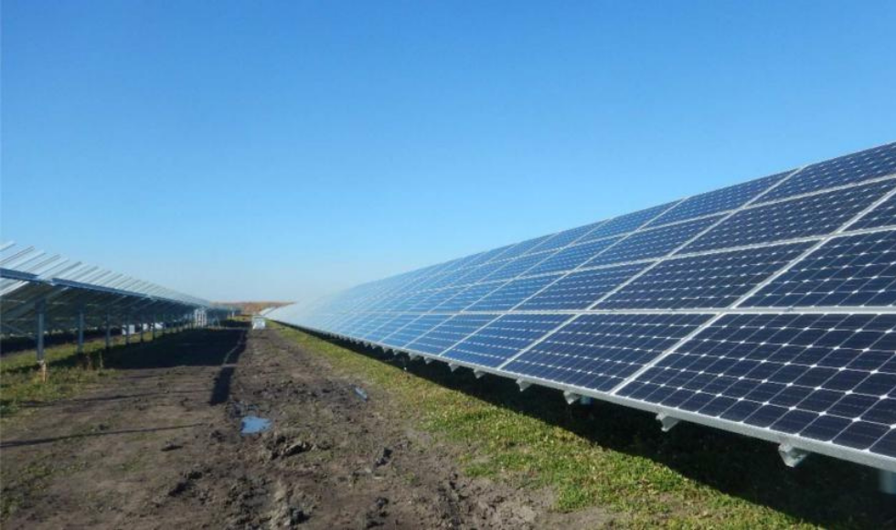 A long row of solar panels in a sunny field.