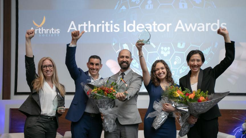 Image of five individuals and award recipients pumping a fist and holding up Arthritis Society award.