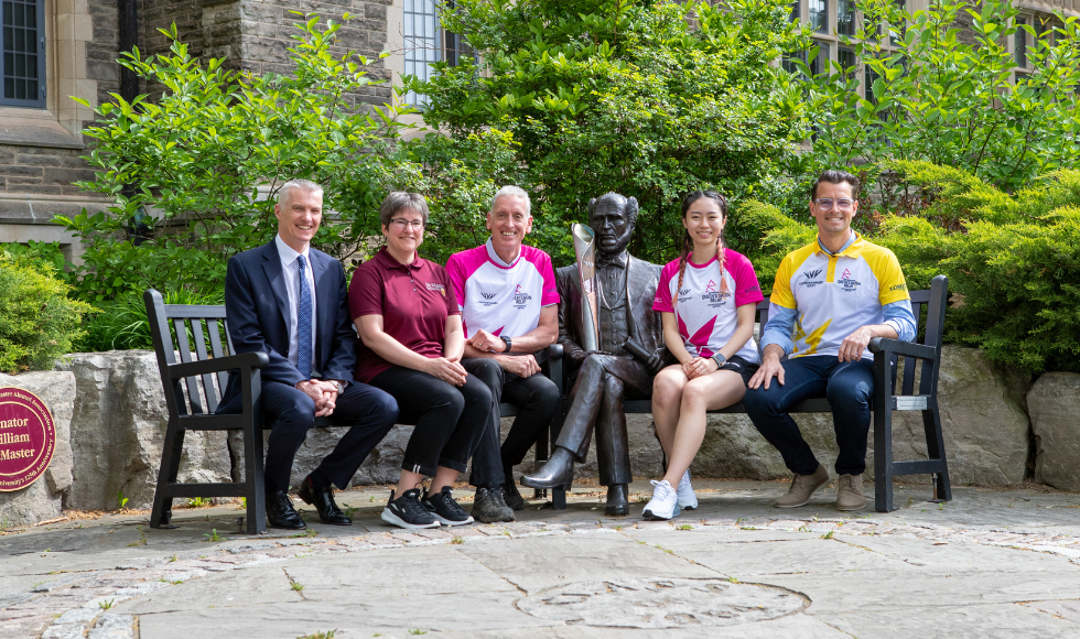Queen's baton being held by researchers and athletes by Senator statue