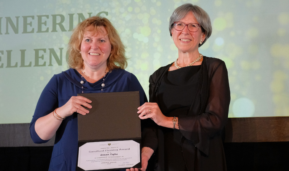 Two smiling women, one holding an award .