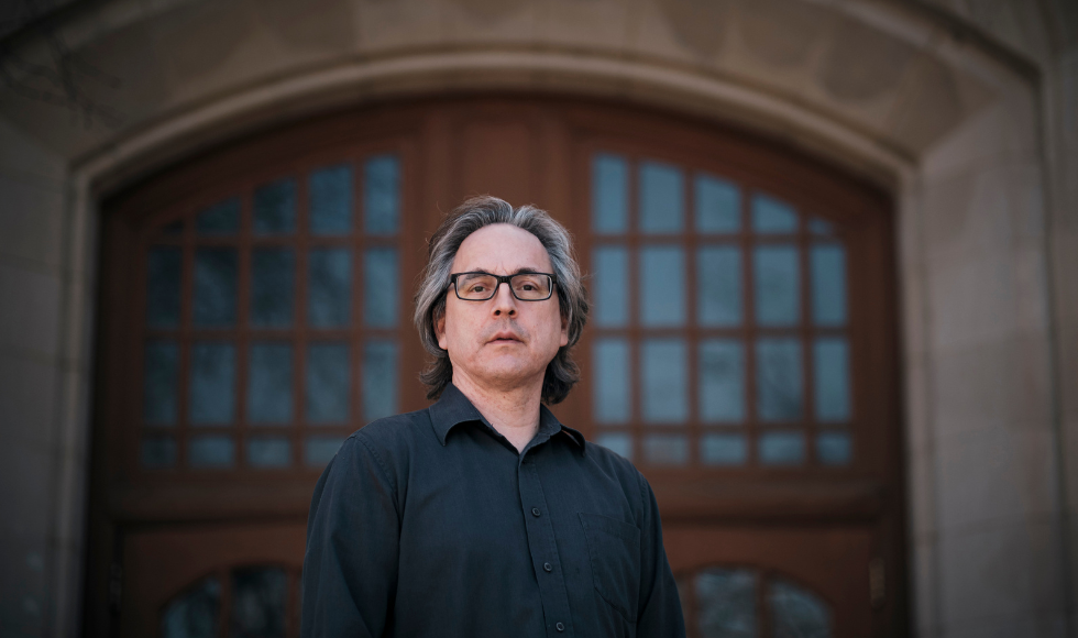 Robert Innes, incoming chair of the newly created Indigenous Studies department at McMaster looks at camera in a dark shirt in front a large door