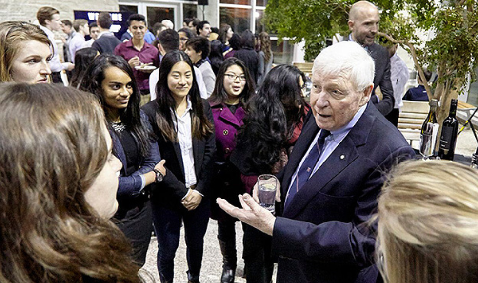 Red Wilson in suit talking to a group of students outside