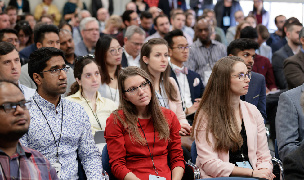 A crowd of people seated all looking at something out of view of the camera