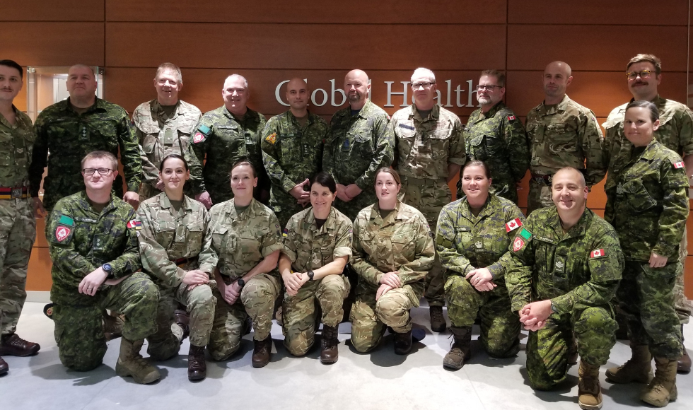 Group shot of about 30 people in military fatigues in front of the Global Health office at McMaster