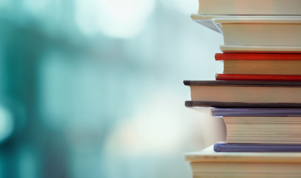 stack of books with sunshine and green background