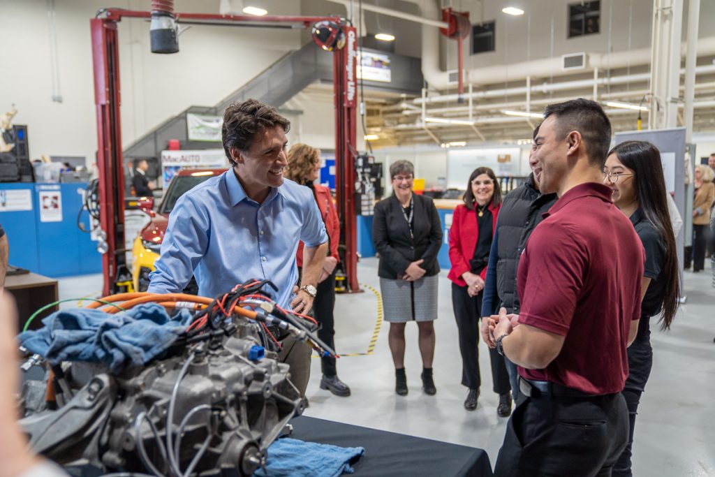 PM Trudeau and student researchers smile as they talk in the McMaster Automotive Resource Centre.