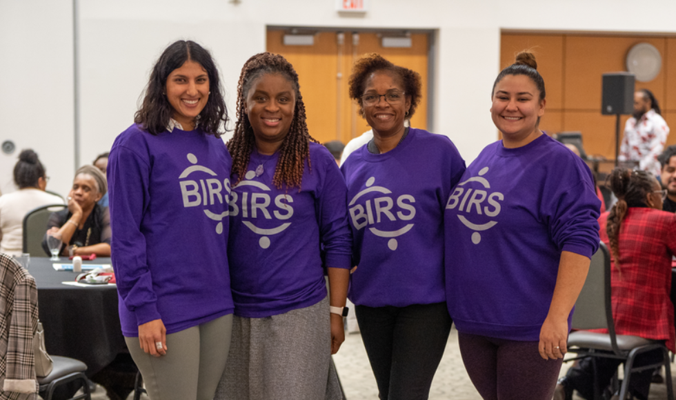 Four people wearing matching purple sweatshirts that read 'BIRS.'