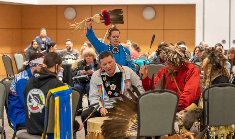 A group of people sitting around a drum during a powwow celebration
