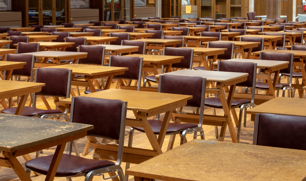 Unoccupied chairs and desks set up in rows in Alumni Hall for exams