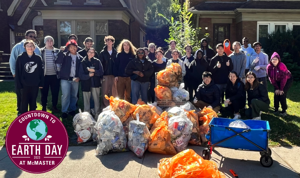 Countdown to Earth Day at McMaster logo and a large group of students poses with full see-through bags after a neighbourhood cleanup
