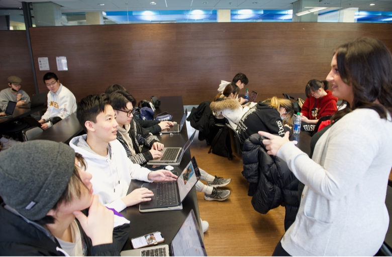 A group of people sitting in a classroom while an instructor speaks