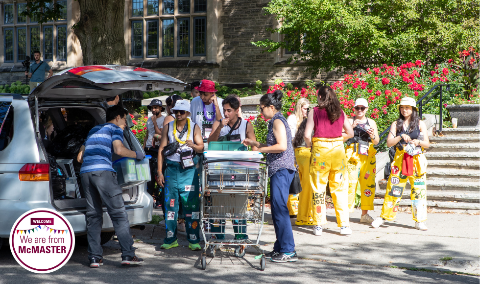 Welcome Week reps in their colourful jumpsuits help a family unload a student's belongings outside University Hall during move-in weekend 2022.