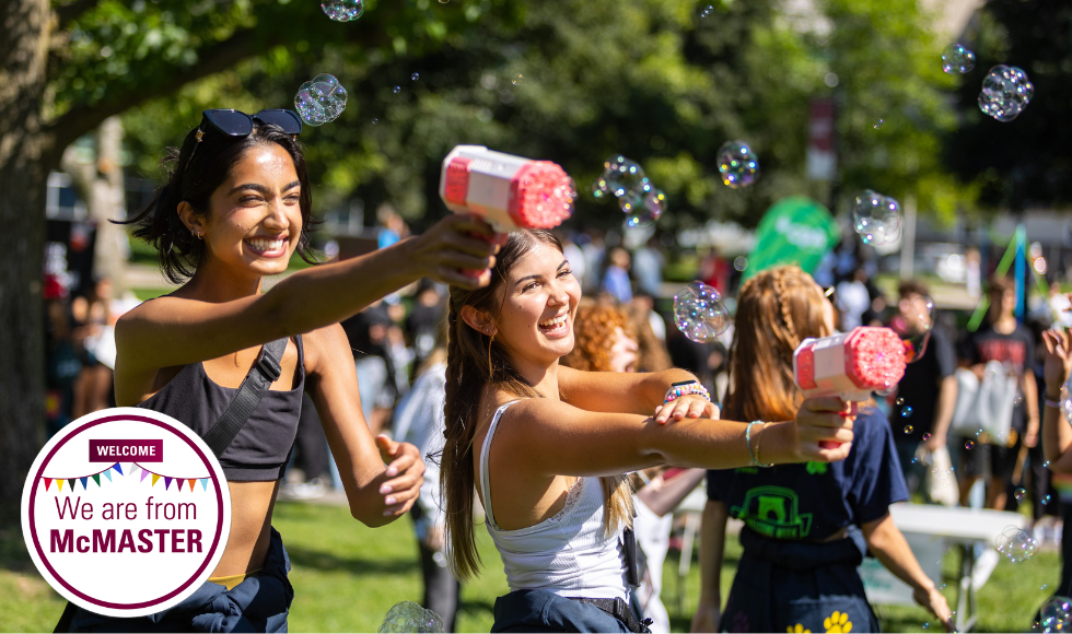 Two smiling McMaster students playing with bubbles guns