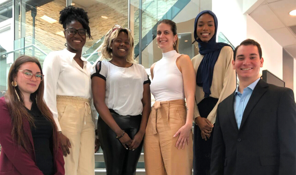 Six people standing on a staircase smiling at the camera