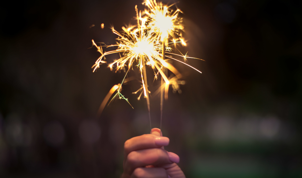 A hand holding a lit sparkler