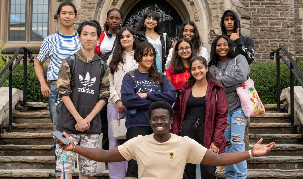 A group of smiling students on the steps of University Hall