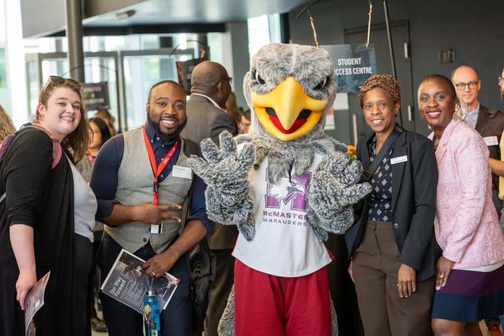 McMaster staff members posing for a photo with the Marauder, the McMaster University mascot