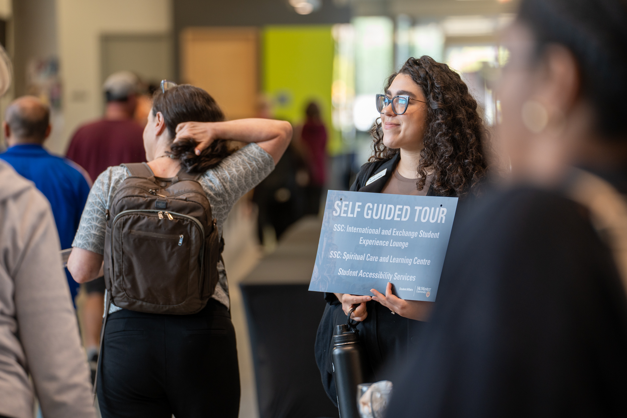 A McMaster staff member holding a sign that reads, 'self guided tour.'